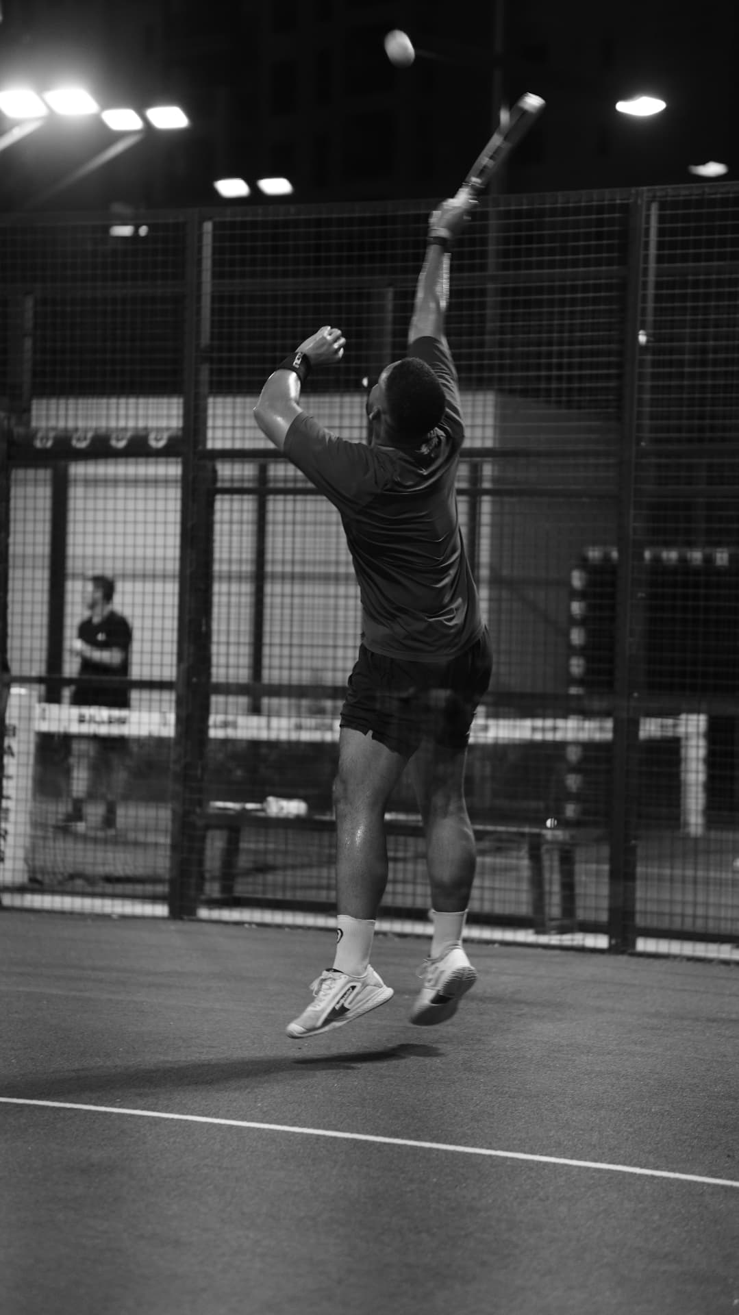 A player jumping to smash the ball on the court at night