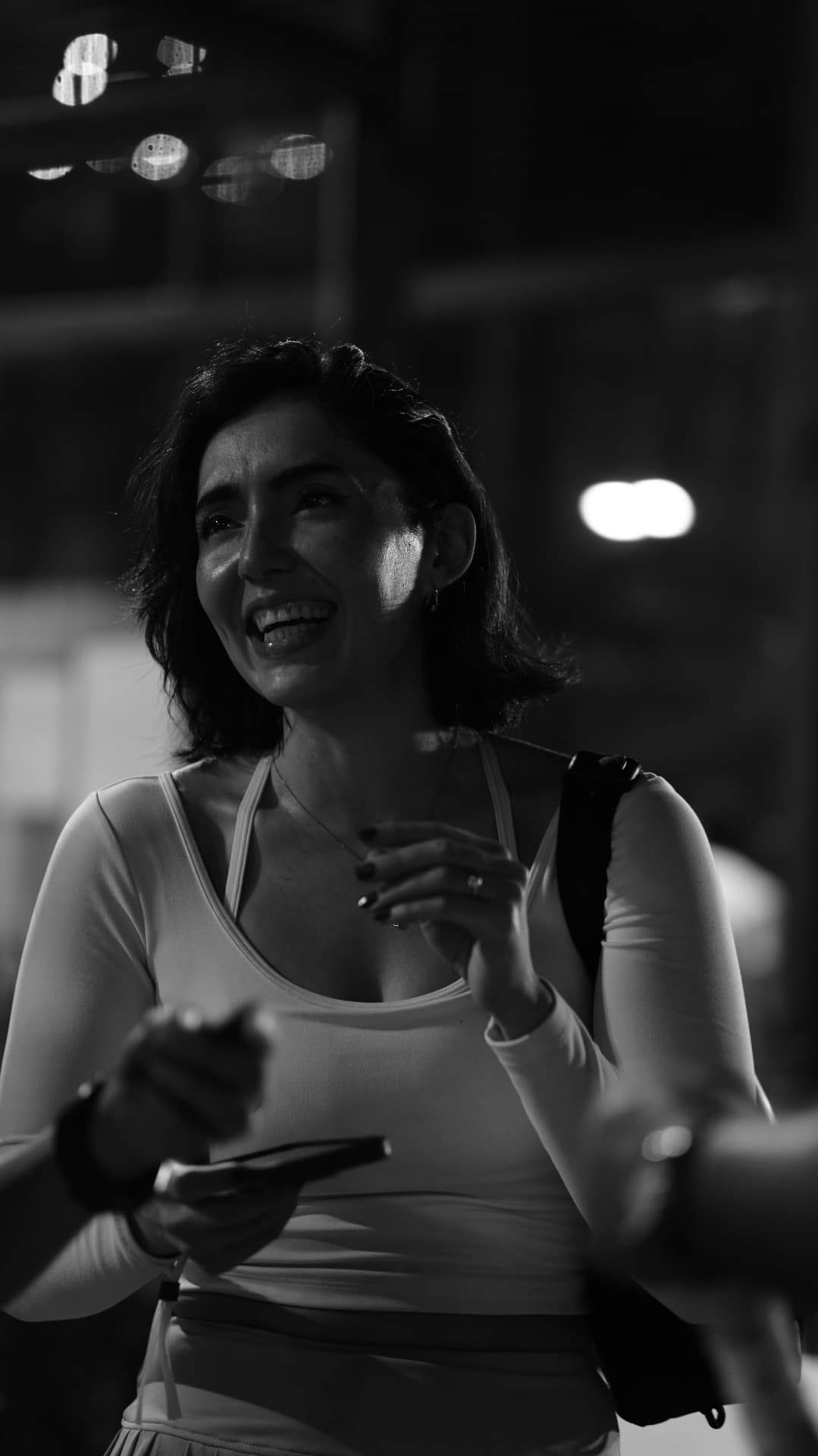 A guest smiling with her phone at the evening gathering