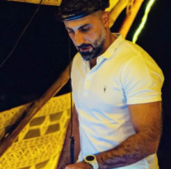 DJ Hamad mixing at night with golden lights behind him